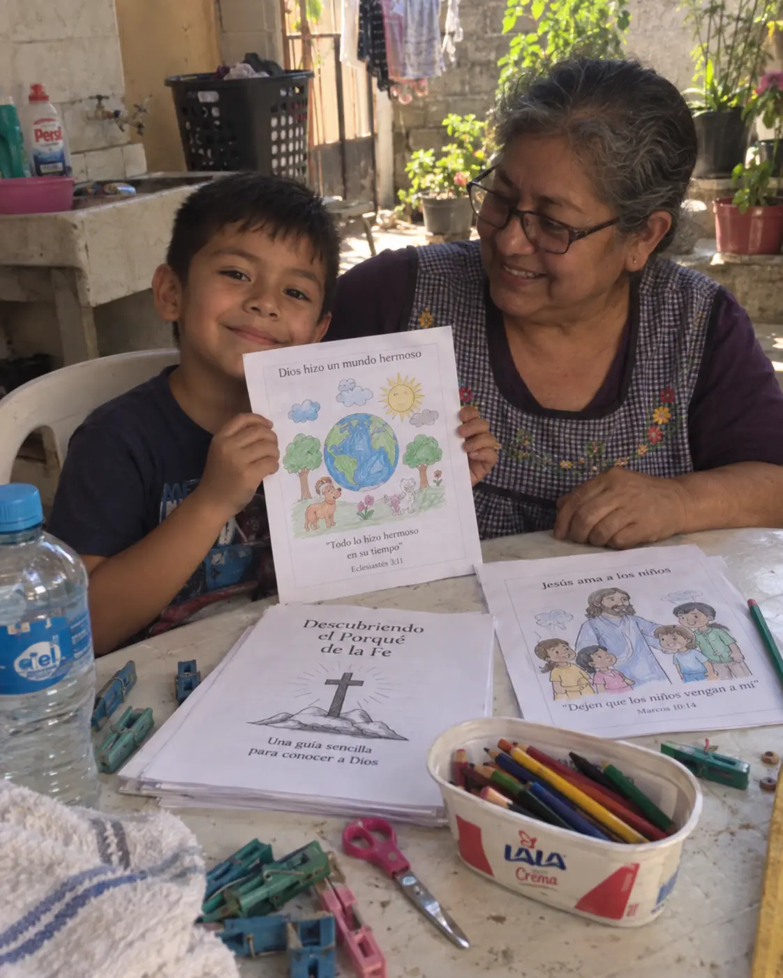 Abuela sonriente junto a su nieto, quien muestra una actividad cristiana coloreada